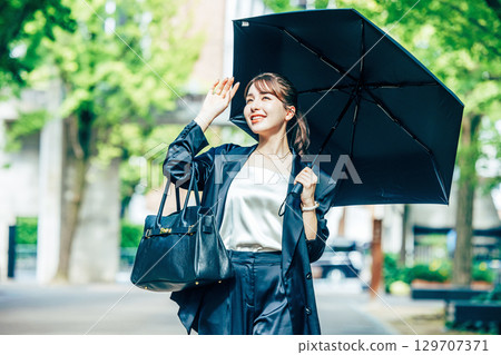 拿著遮陽傘的年輕女商人 129707371
