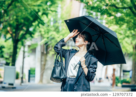 拿著遮陽傘的年輕女商人 拿著遮陽傘的年輕女商人 129707372