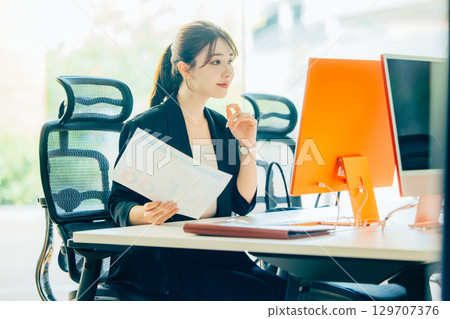 A young business woman operating a personal computer in the office A young business woman operating a personal computer in the office 129707376