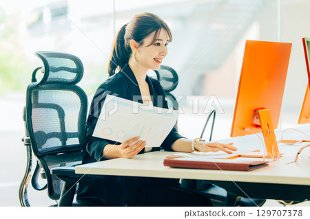 A young business woman operating a personal computer in the office 129707378