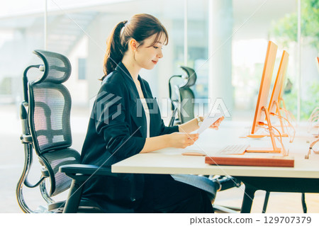A young business woman operating a personal computer in the office 129707379