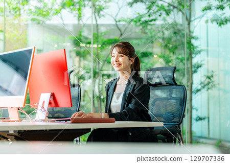 A young business woman operating a personal computer in the office 129707386