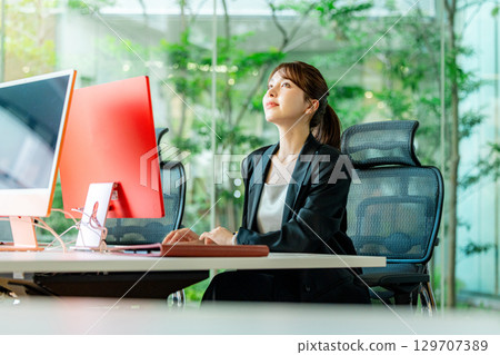 操作一台個人計算機的一個年輕女商人在辦公室 129707389