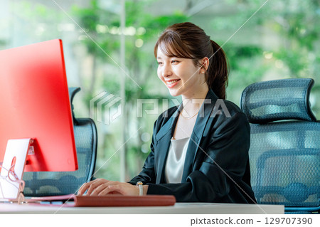 A young business woman operating a personal computer in the office 129707390