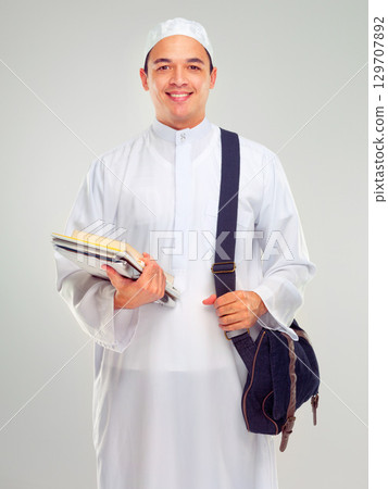 Muslim man, islamic student and standing ready for religious studying, worship or spiritual education in white background. Arabic person, happy and books or culture lifestyle isolated in studio 129707892