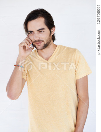 Man, phone and phone call in studio, happy and relax while standing against white background space. Young, handsome and casual guy enjoying call, conversation and speaking while chilling and isolated 129708095