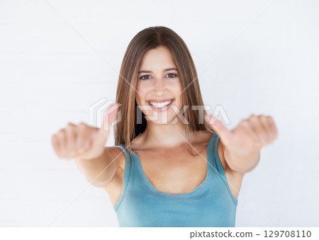 Portrait, young woman and thumbs up for celebration, feedback and lady isolated on white studio background. Female, girl and gesture for success, goal and winner with motivation, wellness or backdrop 129708110
