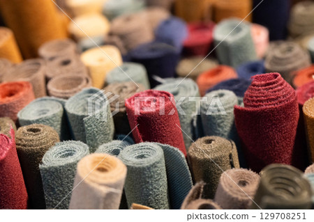Colorful rolls of fabric stacked together in a vibrant display showcasing various textures and patterns 129708251
