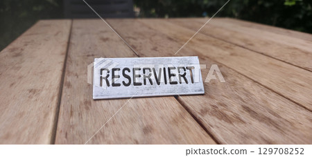 Reserved sign on wooden table surface, indicating a designated space for guests or diners 129708252