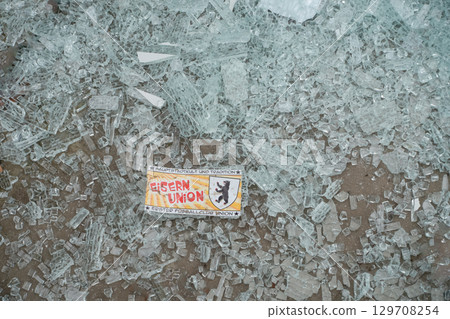 Shattered glass pieces scattered on ground with a colorful sticker in the center Shattered glass pieces scattered on ground with a colorful sticker in the center 129708254