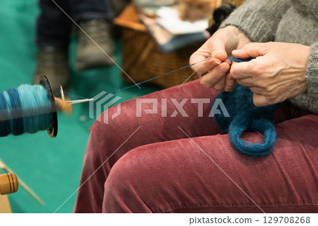 Skilled artisan spinning yarn with a spinning wheel, showcasing traditional craftsmanship and creativity 129708268