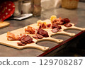 Assorted cured meats displayed on wooden boards in a rustic kitchen setting with vibrant colors 129708287
