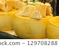 Cheese wheels with cut pieces displayed at a market showcasing fresh dairy products and textures 129708288