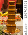 Chocolate fountain with flowing melted chocolate surrounded by fresh fruits and desserts 129708291