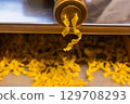 Freshly made pasta extruding from a machine onto a surface in a culinary setting 129708293