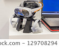 Virtual reality headset mock up displayed on a stand beside a laptop with a blue screen 129708294