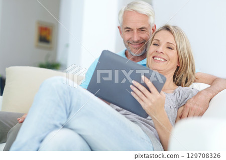 Mature couple, tablet or relax on sofa in house or home living room on social media or internet app. Happy smile, retirement man or woman on digital technology for video call, movie streaming or news 129708326