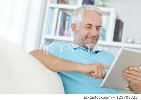 Mature man, digital tablet or relax on sofa in house, home or apartment living room on social media app or internet game. Smile, happy or retirement person on technology crossword puzzle or streaming Mature man, digital tablet or relax on sofa in house, home or apartment living room on social media app or internet game. Smile, happy or retirement person on technology crossword puzzle or streaming 129708328