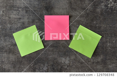 Three sticky notes in pink and green sit on a dark backdrop Three sticky notes in pink and green sit on a dark backdrop 129708348