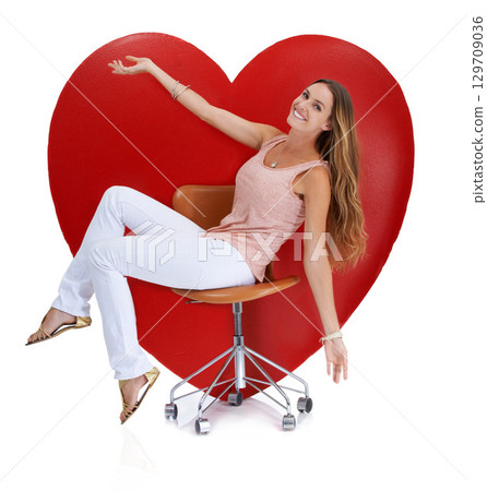 Portrait, studio and woman on chair by big heart isolated on a white background. Beauty, love and happy female model sitting near symbol for romance, affection or romantic emoji, care or empathy. 129709036
