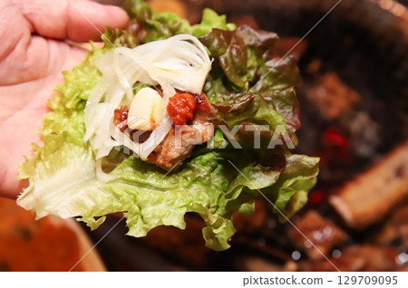 Korean bbq. ssam : eat pork wrapped in lettuce leaves 129709095