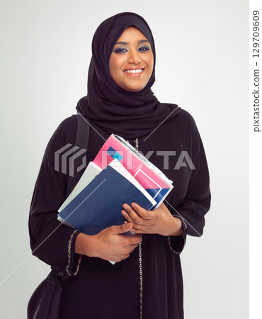 Portrait, muslim and books with a student woman in studio on a gray background for learning or education. Islam, university and study with an islamic female at college to study on a scholarship 129709609