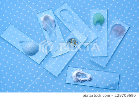 Samples of multi-colored cosmetic products on a blue polka dot background. 129709690