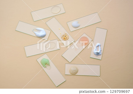 Textures of various cosmetic products on slides on a beige background. Textures of various cosmetic products on slides on a beige background. 129709697