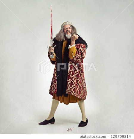 King, blood sword and man in celebration in studio isolated on a gray background mockup. Villain, royal winner and mature male or evil ruler with bloody blade celebrating battle, victory or success. 129709814