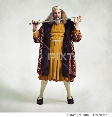 King, portrait and man lick sword in studio isolated on gray background mockup. Victorian villain, medieval royal and mature male, evil ruler or crazy leader licking steel blade after battle or fight 129709832