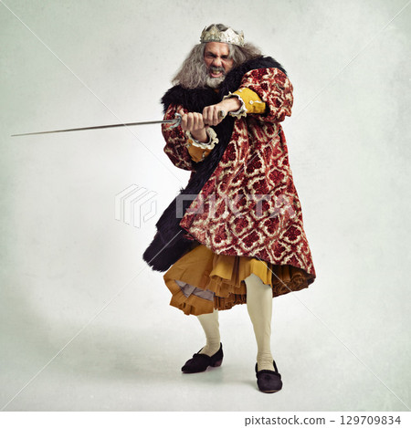 Man, royalty and portrait of king with sword in studio isolated on a gray background mock up. Vintage victorian, evil and mature mad male, angry ruler and leader holding blade for battle or fight. Man, royalty and portrait of king with sword in studio isolated on a gray background mock up. Vintage victorian, evil and mature mad male, angry ruler and leader holding blade for battle or fight. 129709834