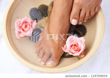 Skincare, flowers and woman with feet in water bowl for cleaning or hygiene. Floral therapy, spa treatment and female model soak foot washing with pink roses and stones for detox, beauty or pedicure. Skincare, flowers and woman with feet in water bowl for cleaning or hygiene. Floral therapy, spa treatment and female model soak foot washing with pink roses and stones for detox, beauty or pedicure. 129709934