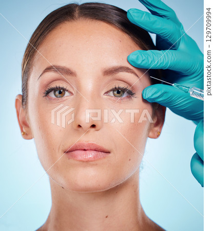Plastic surgery, skincare and woman with injection, healthcare and on blue studio background. Female, girl and botox with cosmetics, wellness and face care for health, soft and smooth skin for beauty Plastic surgery, skincare and woman with injection, healthcare and on blue studio background. Female, girl and botox with cosmetics, wellness and face care for health, soft and smooth skin for beauty 129709994