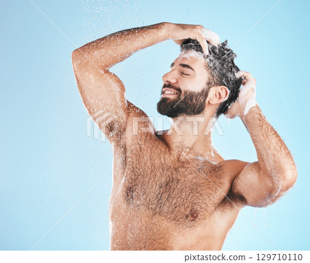 Hair, shampoo and cleaning with a man in studio on a blue background to take a shower for hygiene. Water, skin and relax with a male washing for haircare or keratin treatment in the bathroom 129710110