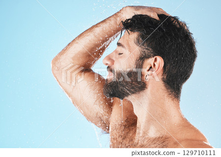 Head, hair and hygiene with a model man using shampoo for cleaning in studio on a blue background. Water, wet and wellness with a handsome male washing for haircare, hydration or keratin treatment 129710111