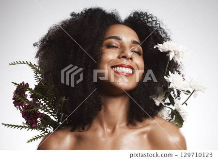 Black woman, beauty and flowers on studio background for healthy skincare. Happy face, floral plants and model with spring perfume, natural makeup and eco wellness for cosmetics, aesthetics and smile 129710123