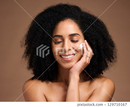 Skincare, cream and black woman with smile for beauty, cosmetics and facial health promotion of product in studio. Happy African model with skin care, dermatology or sunscreen application on her face 129710167