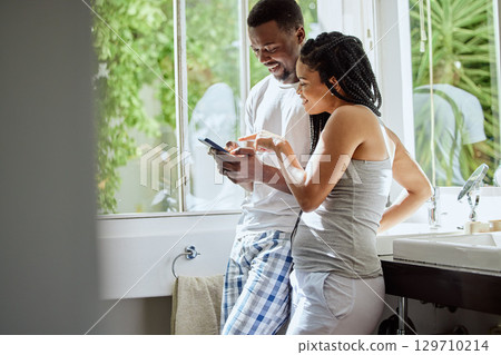 Phone, morning and black couple in bathroom in home on social media, networking or internet. Relax, pointing and happy man and woman on mobile smartphone for online shopping or streaming video. 129710214
