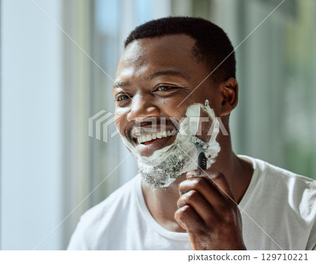 Face, shaving and razor with a black man grooming in the bathroom mirror of his home for beauty or skincare. Beard, shave and blade with a handsome male in the morning for his hair removal routine Face, shaving and razor with a black man grooming in the bathroom mirror of his home for beauty or skincare. Beard, shave and blade with a handsome male in the morning for his hair removal routine 129710221