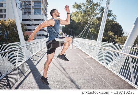 Fitness, running and exercise with a sports man on a bridge in the city for a cardio or endurance workout. Health, runner and training with a male athete exercising in an urban town for wellness 129710255