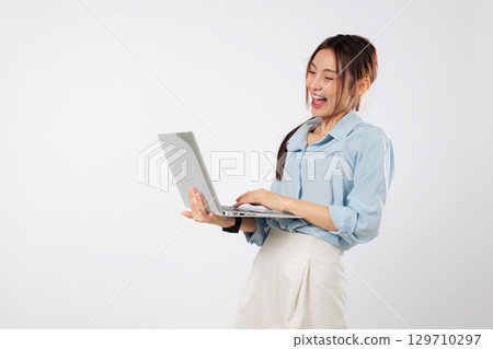 Laptop in front of happy Asian woman positive typing with smile, focused and excited while using second laptop on her desk for multitasking. isolated studio white background 129710297