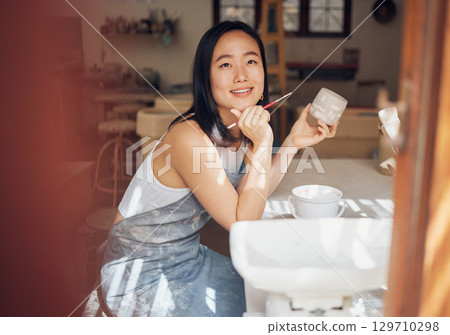 Asian woman, pottery and thinking while painting in workshop, creative studio and design startup. Happy female painter, clay ceramics and brush ideas, artistic pattern and dreaming in small business 129710298