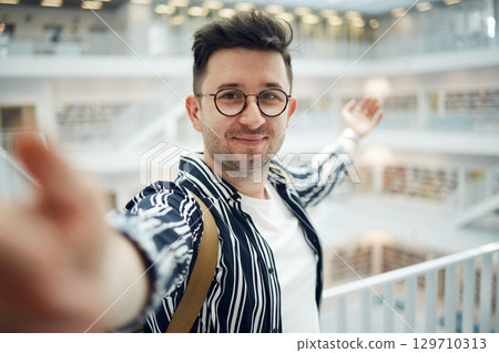 Library, student selfie and man in university, college or school. Education scholarship, learning and face portrait of young male taking a photo or picture for memory, social media or online profile. Library, student selfie and man in university, college or school. Education scholarship, learning and face portrait of young male taking a photo or picture for memory, social media or online profile. 129710313