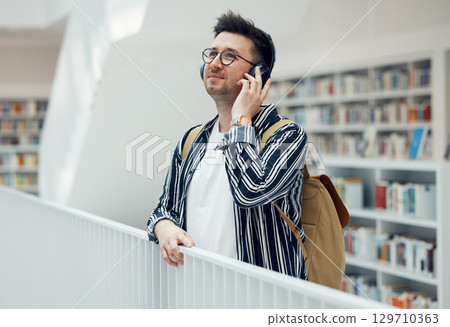 Headphones, college student man and university library work or research for learning. School campus building, music and live song streaming of a person looking for study books 129710363