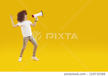 Happy preteen boy shouting into megaphone making announcement. 129710366