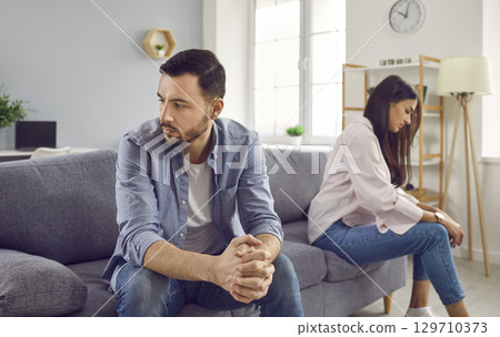 Disappointed couple sitting on sofa back to back, facing away from each other Disappointed couple sitting on sofa back to back, facing away from each other 129710373