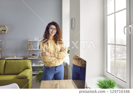 Portrait of smiling businesswoman standing with arms folded Portrait of smiling businesswoman standing with arms folded 129710386