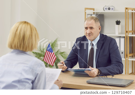 USA Consulate or Immigration Services worker talking to woman about visa or immigration USA Consulate or Immigration Services worker talking to woman about visa or immigration 129710407
