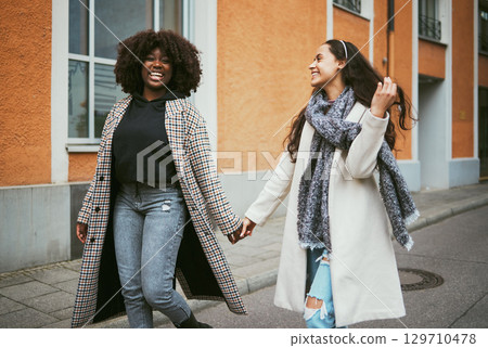 Travel, holding hands and lesbian couple walking in street enjoying holiday, vacation and adventure. Fashion, lgbtq relationship and women dating for happy lifestyle, freedom and relaxing on weekend 129710478