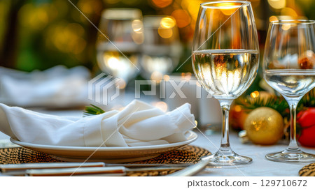 Elegant dining table setting with glasses, white napkin, and festive decorations for celebration 129710672